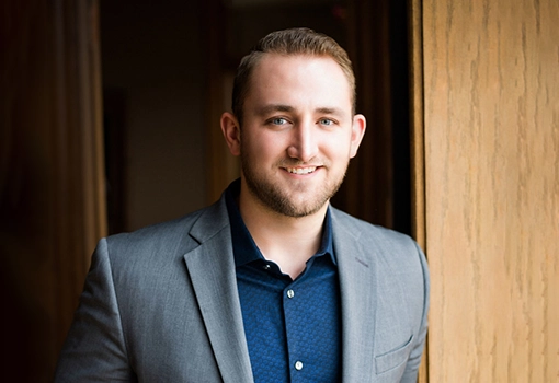 Chiropractor Justin Brazda Smiling In Suit And Standing In Doorway